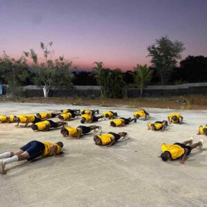 Group of students doing push-ups at sunset.